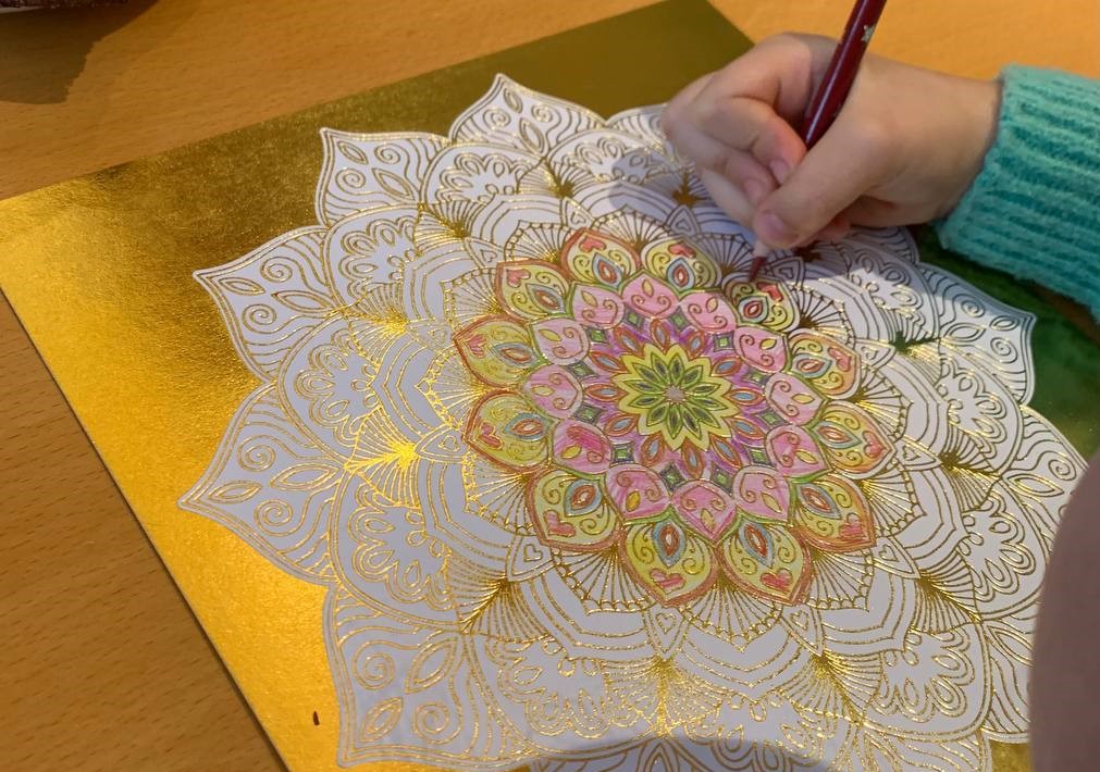 Refugee from Ukraine is coloring Mandala with pencil